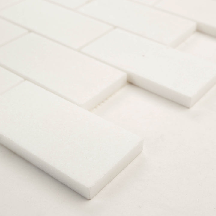 2x4 brick mosaic in polished Thassos White marble, shown corner-on to reflect its bright surface and precise spacing.