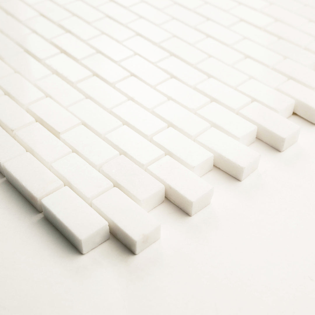 Thassos White marble 5/8 x 1-1/4 brick mosaic, polished, viewed from a corner to highlight its brilliant shine and fine geometric layout.
