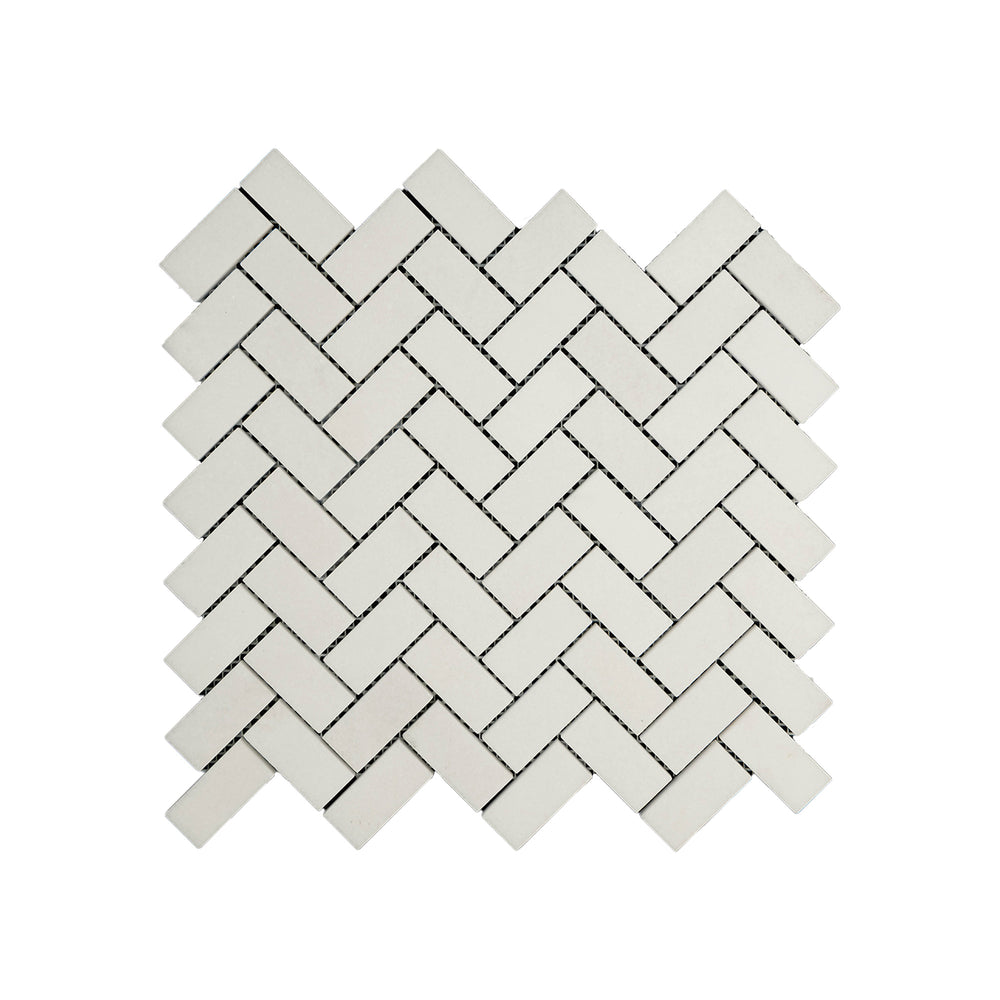 Top-down view of Thassos White Marble 1x2 herringbone mosaic in honed finish, featuring diagonal tile layout with a smooth matte surface and bright white tone.