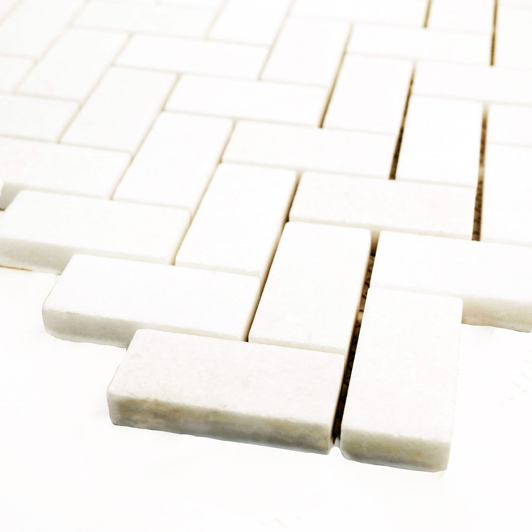 1x2 herringbone mosaic in honed Thassos White marble, corner shot reveals dynamic patterning and satin finish.