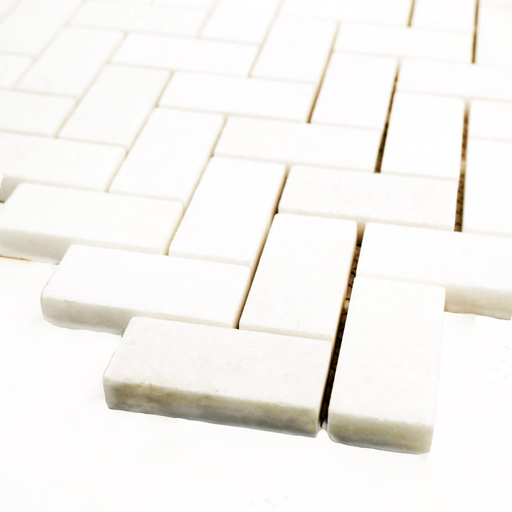 1x2 herringbone mosaic in honed Thassos White marble, corner shot reveals dynamic patterning and satin finish.