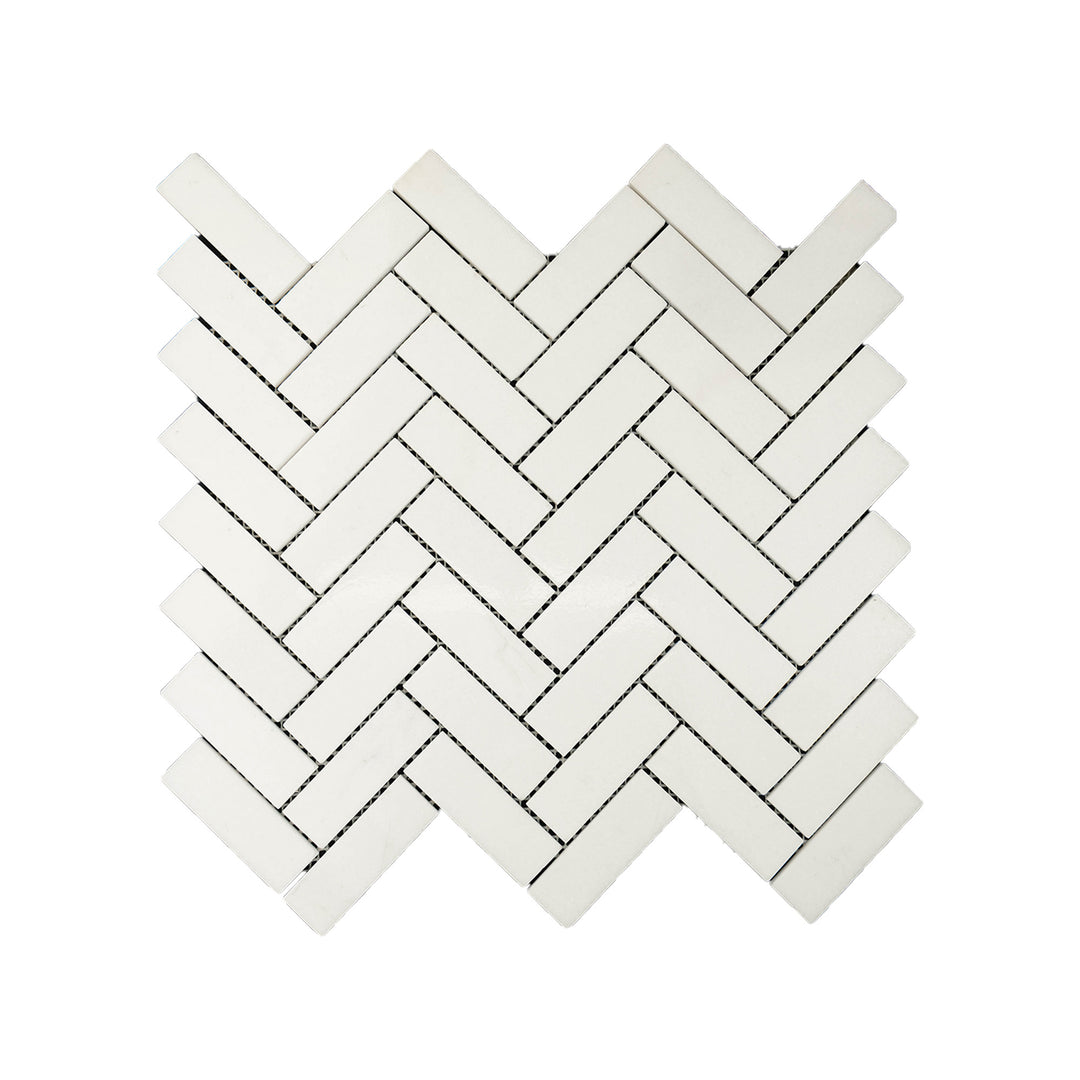 Polished 1x3 herringbone mosaic in Thassos White Marble seen from above, delivering clean symmetry and high-gloss surface in crisp white.