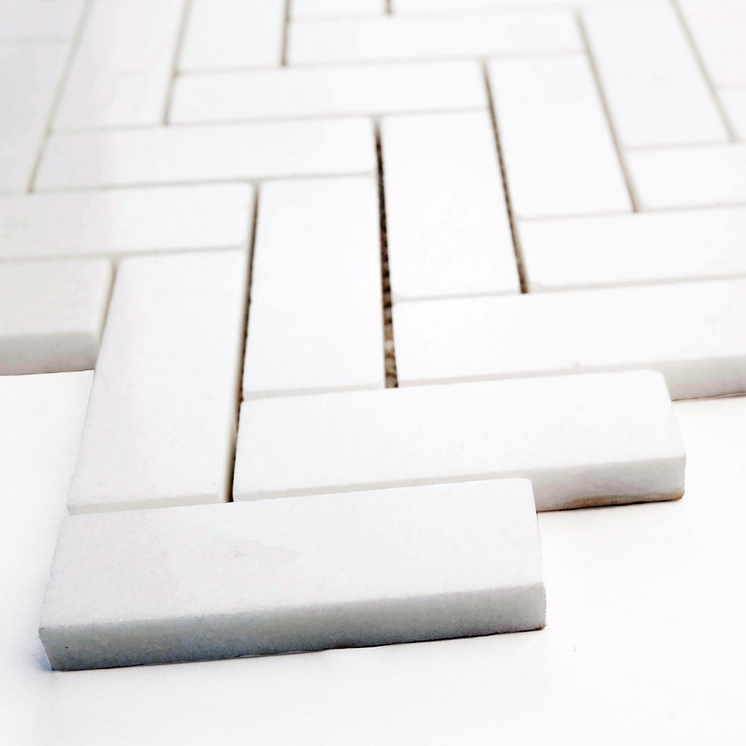 1x3 herringbone polished mosaic in Thassos White marble, angled view brings out elegant shine and distinctive zigzag pattern.