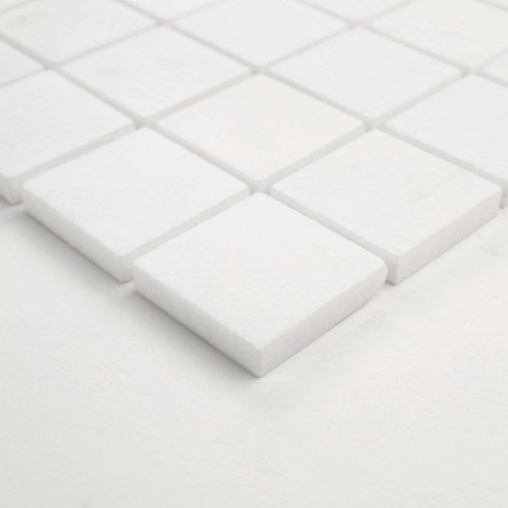 Angled view of Thassos White Marble 2-Inch Square Honed Mosaic Tile, displaying a natural matte look and balanced layout—ideal for contemporary bathrooms and kitchens.