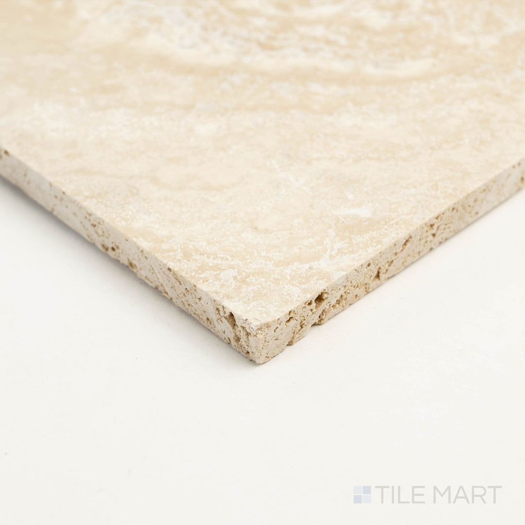 Corner detail of Ivory Premium Travertine 18x18 tumbled tile highlighting organic surface and warm beige coloration.