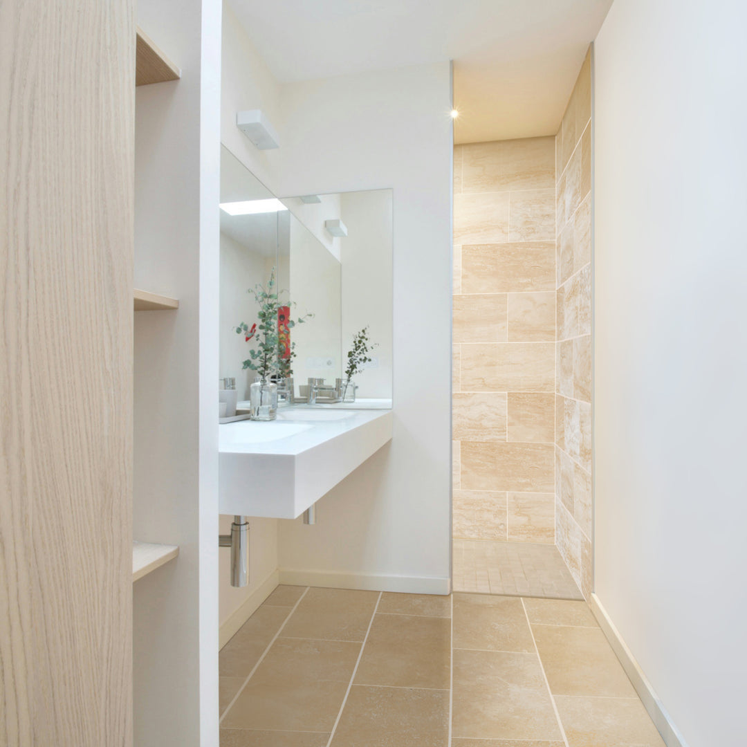 Modern bathroom with tiled floor and wall, featuring a sink and mirror.