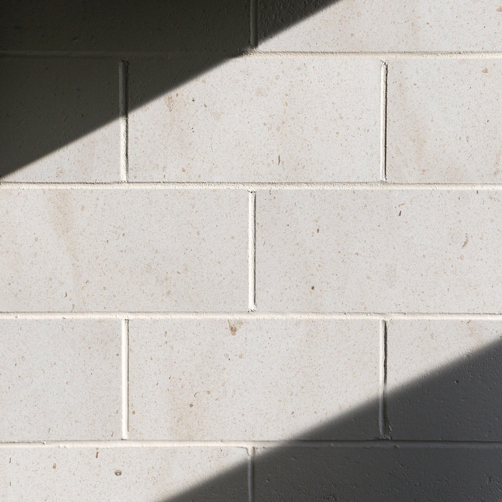 Close-up of light gray tiles with shadows on a wall