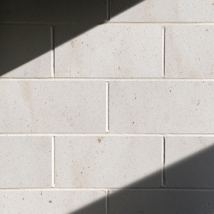 Close-up of light gray tiles with shadows on a wall