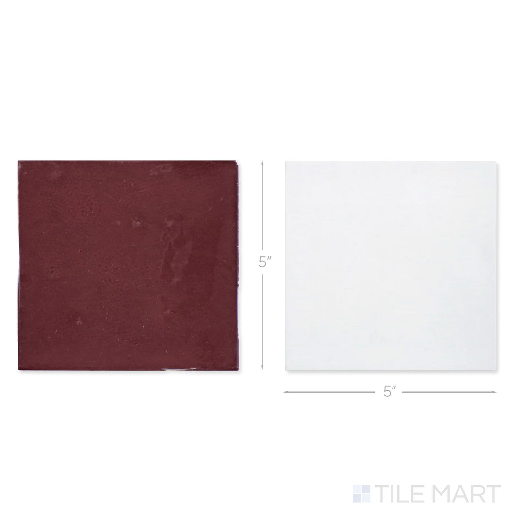 Top-down view of a single Village 5x5 white and aubergine checkerboard glossy ceramic tile showing its light-reflective surface and two-tone finish detail