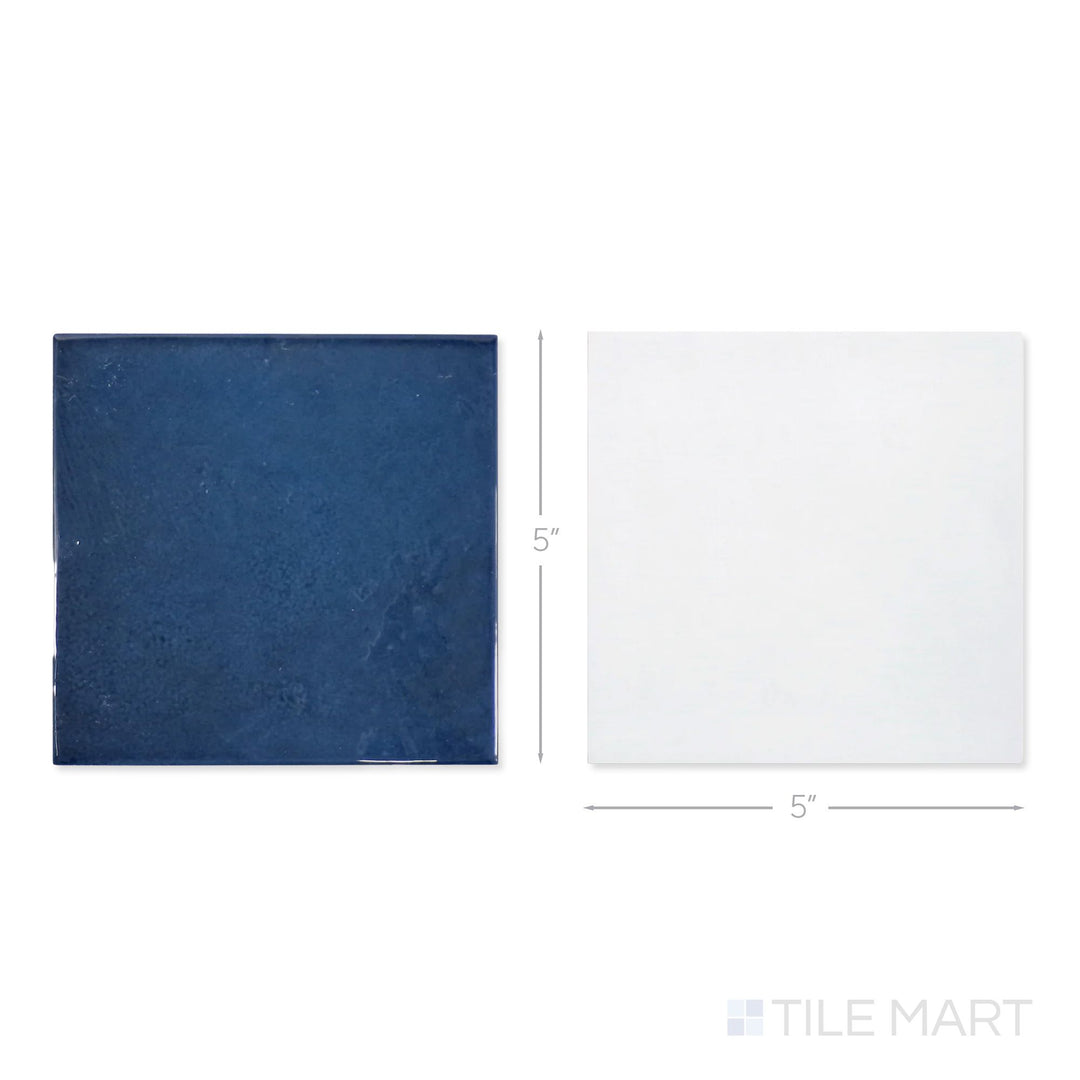 Top-down view of a single Village 5x5 white and royal blue checkerboard glossy ceramic tile showing its light-reflective surface and two-tone finish detail