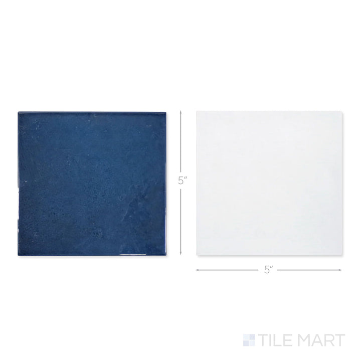 Top-down view of a single Village 5x5 white and royal blue checkerboard glossy ceramic tile showing its light-reflective surface and two-tone finish detail
