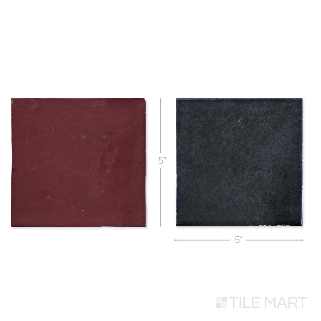 Top-down view of a single Village 5x5 aubergine and black checkerboard glossy ceramic tile showing its light-reflective surface and two-tone finish detail