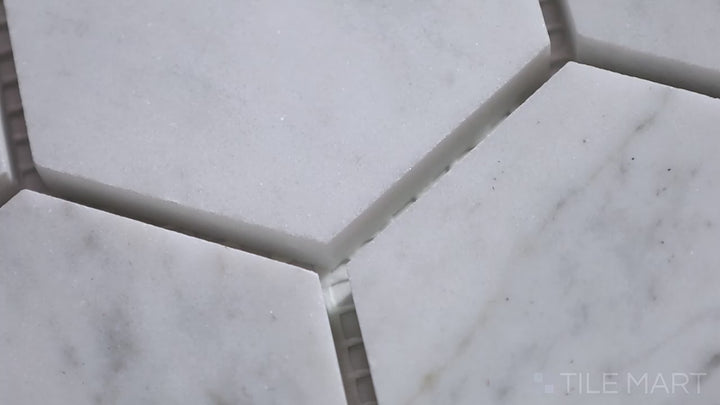Video showcasing Sto-Re Carrara 2-1/2" Hexagon Polished Marble Mosaic. Classic Carrara marble with a refined polished finish, laid out in an elegant large hexagonal pattern.